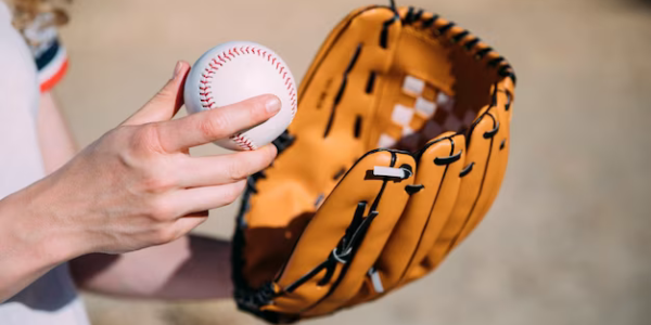 Hand holding a baseball and glove, close-up view