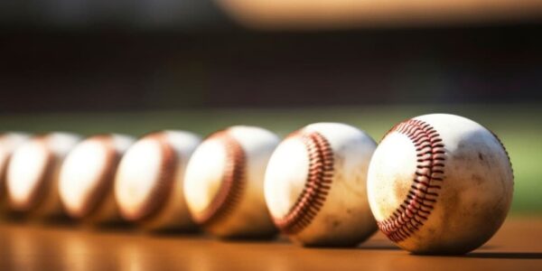 A row of used baseballs on a sunlit wooden surface