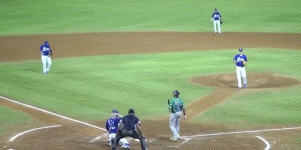 A baseball game in progress with the pitcher preparing to throw to a batter in a green jersey