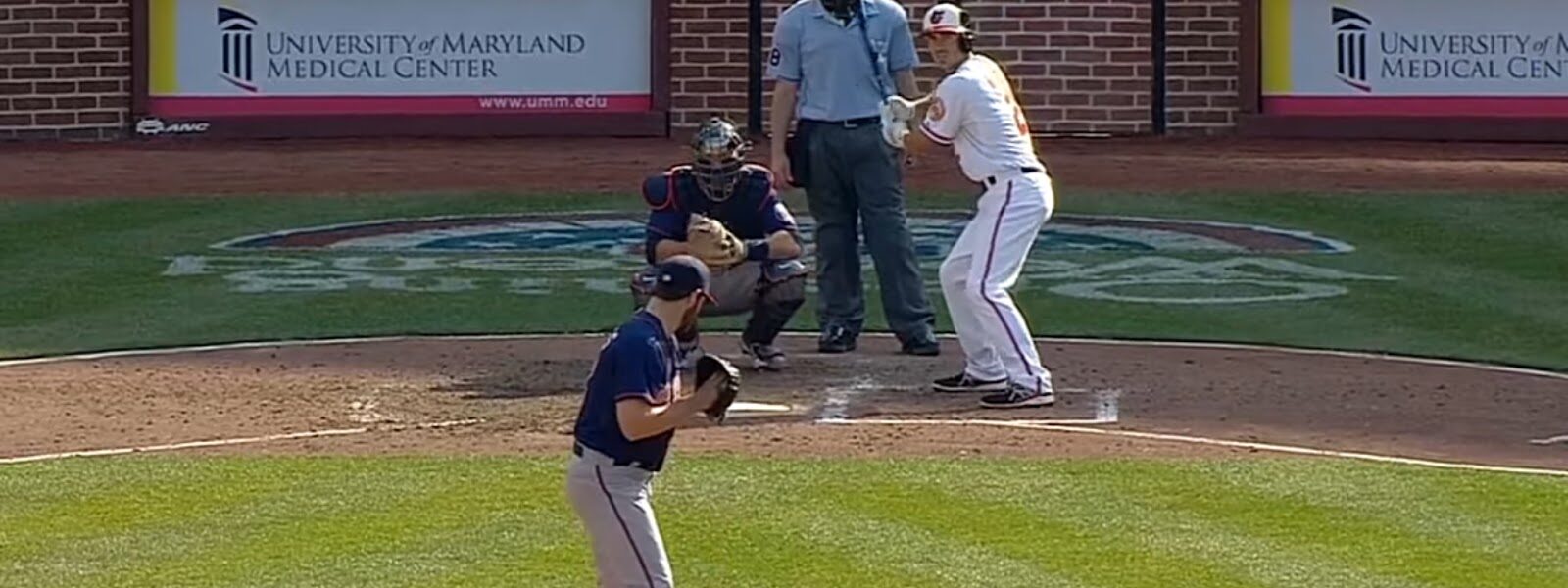 A pitcher facing a batter during a baseball game with the scoreboard showing a tied score