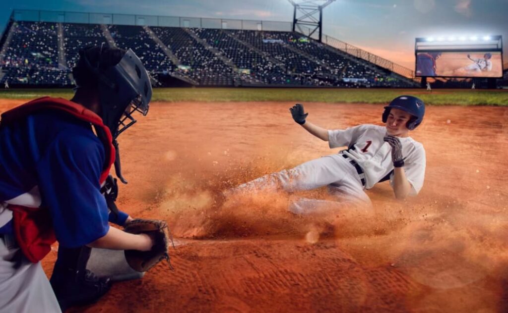 A base runner in white slides into home plate against a catcher